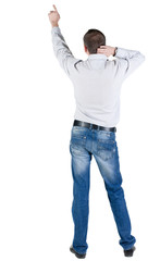 Back view of young man pointing at wall.