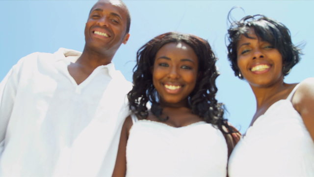African American girl with parents skyping on beach vacation 