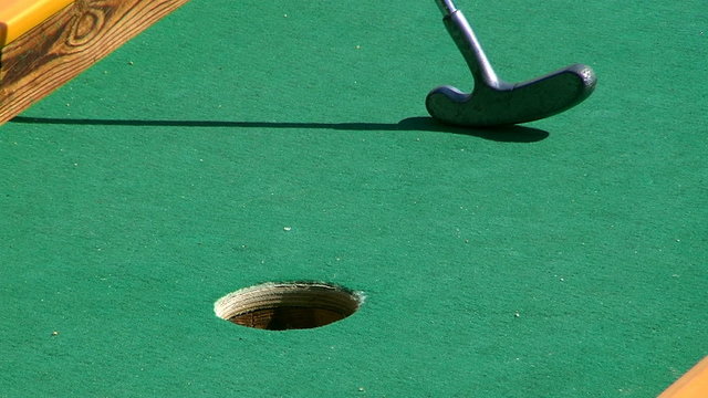 Golf stick and ball on green grass close up.