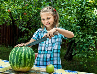Fototapeta premium Young girl cut ripe watermelon