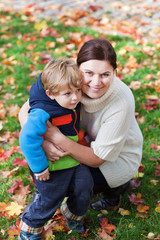 Little toddler boy and young mother in the autumn park