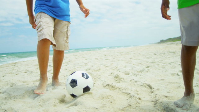 African American boys playing soccer ball on beach shot on RED EPIC
