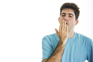 Naklejka premium Yawning young man with blue shirt isolated on white background