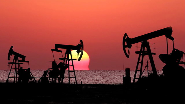 working oil pumps silhouette against timelapse sunrise