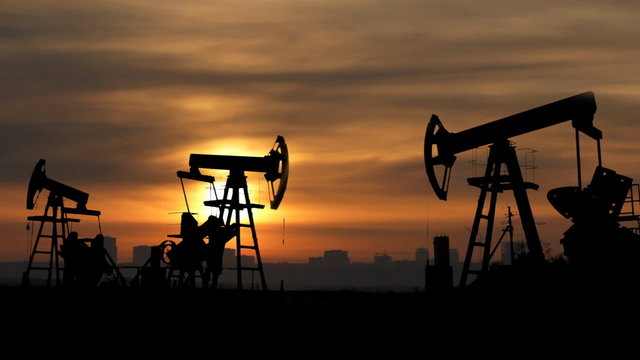 working oil pumps silhouette against sunrise