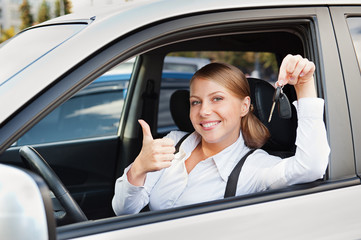 woman holding car key and showing thumbs up