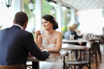 Young happy bride and groom sitting at an outdoor cafe