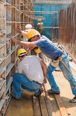 Construction builders positioning concrete formwork frames - 45898333