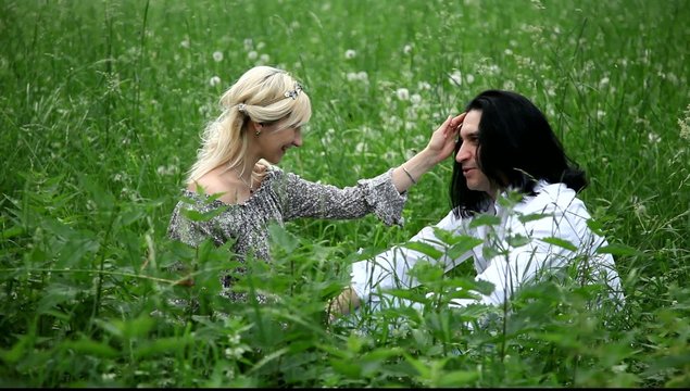 Беременная женщина и мужчина сидят в траве