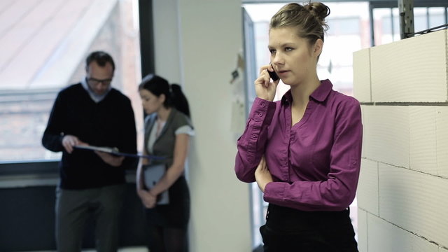 Young businesswoman talking on mobilephone in the office corrido