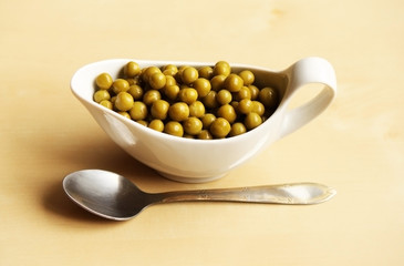 Green peas in a little plate with a spoon