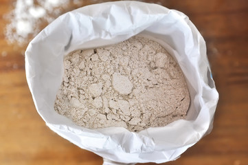 Rye  flour in  paper bag  on the wooden table