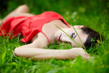 beautiful  brunette girl lying in green summer bright grass