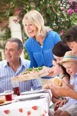 Senior Woman Serving At Multi Generation Family Meal