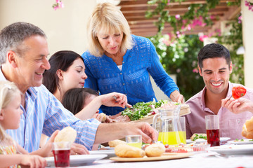 Senior Woman Serving At Multi Generation Family Meal