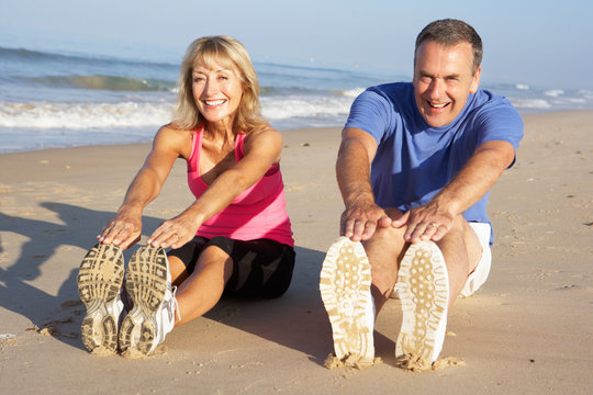 Senior Couple Exercising On Beach - Powered by Adobe