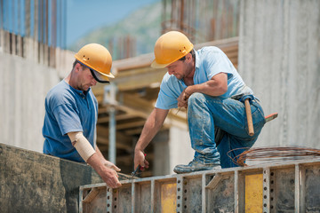 Two construction workers installing concrete formwork frames - 45924506