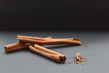 Cinnamon sticks and ground cinnamon on grey and black background