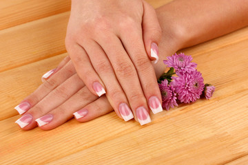 Fototapeta premium Woman hands with french manicure and flowers