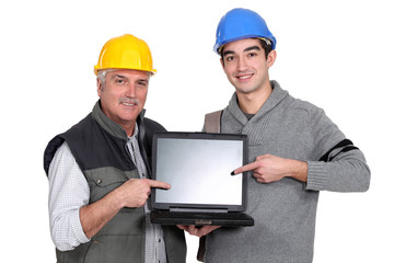 Builder and youth worker pointing at laptop