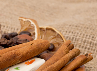 Sweets, cinnamon, nuts and coffee beans on a saucer, on burlap b