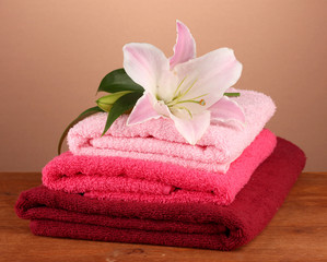 Obraz na płótnie Canvas stos ręczniki z różowego lily na brązowym tle