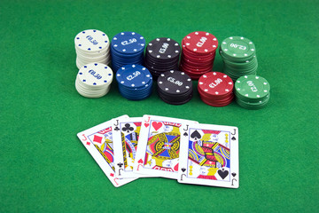 Poker chips and cards isolated against green felt
