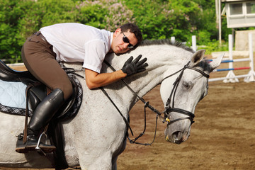 Jockey in glasses hug horse on hippodrome