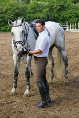 Jockey stand near horse feed him on hippodrome
