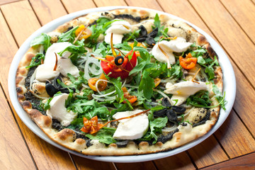 Black olive and rucola pizza with fresh mozzarella.
