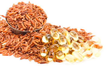 pile grain brown rice with oil pills isolated on the white backg