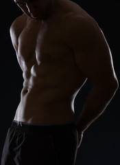 Fototapeta na wymiar Closeup on male athlete showing muscular body on black