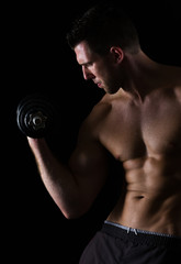 Fototapeta na wymiar Strong muscular sports man rising dumbbell on black