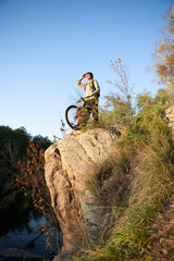 Fototapeta na wymiar Człowiek z roweru stojącego na skale. Jesień natura