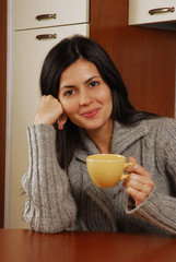 Joven mujer bebiendo una taza de tè o café en casa.