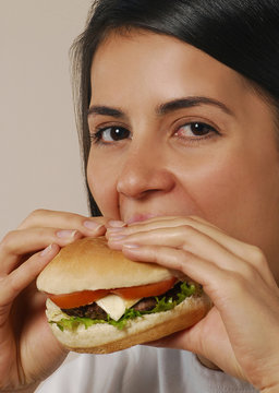 Joven mujer comiendo hamburguesa.