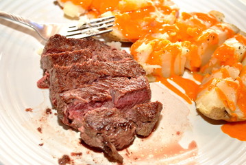 Rare Sliced Filet Mignon and French Dressing on a Baked Potato