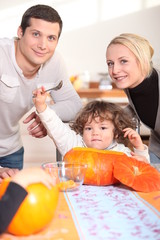 a little child  eating a pumpkin and his parents