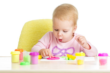 Little kid sitting at table playing with colorful clay