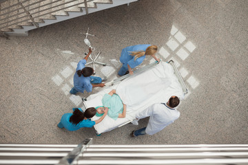Three nurses and one doctor pushing one patient in a bed