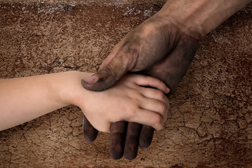 black dirty man hands holding kid clean hand