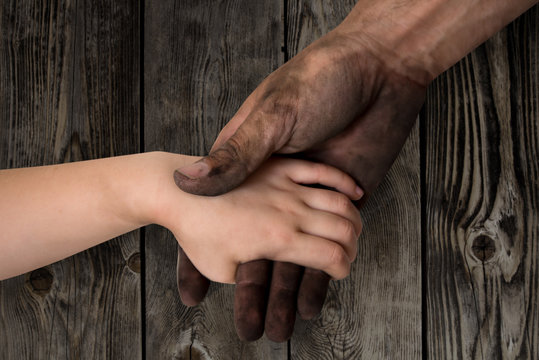 black dirty man hands holding kid clean hand