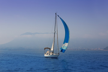 Blue sea with sailboat sailing in a foggy coast