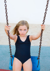 blond girl swinging on blue swing with swimsuit