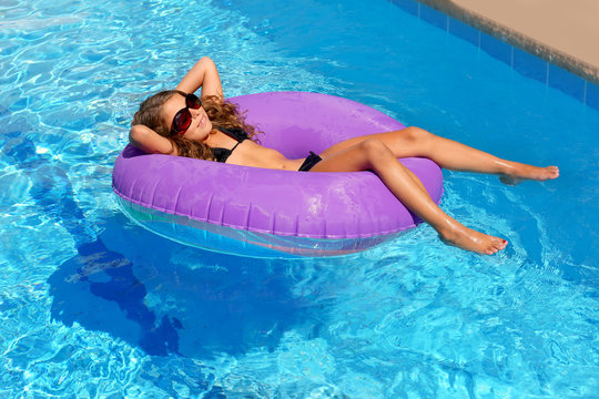 children girl relaxed on purple inflatable pool ring