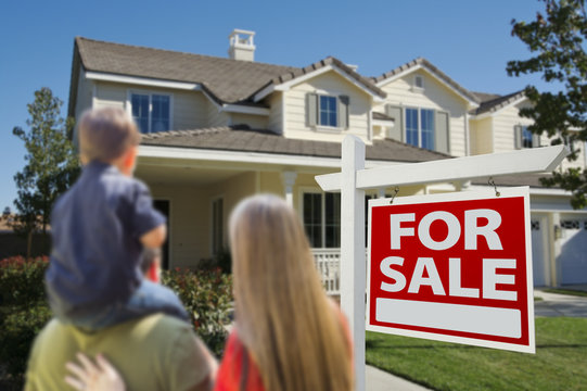 Family Looking at New Home with For Sale Sign