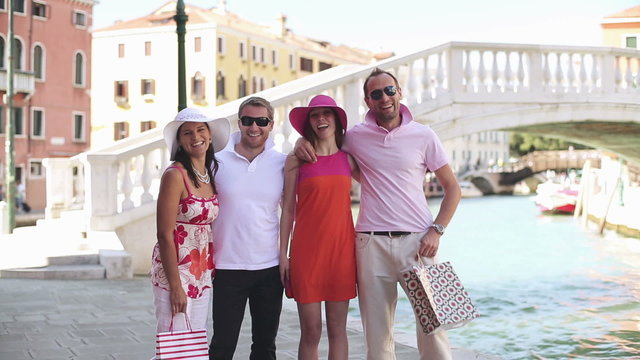 Four happy rich friends with shopping bags in Venice 