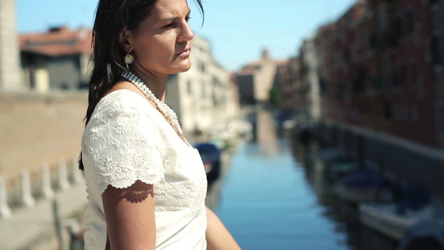 Beautiful sad bride standing alone on the bridge in Venice 