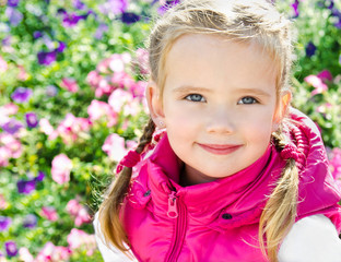 Outdoor portrait of cute little girl near the flowers