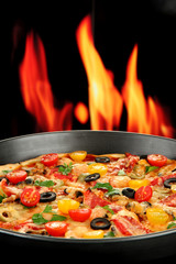 Delicious pizza with seafood on fire background